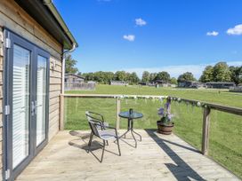 An outdoor area with a table and chair at Angel Lodge - No 27, Fornham St Genevieve near Bury St Edmunds