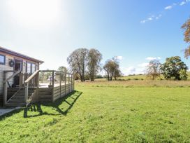 An outdoor view of a wooden deck and grassy field at Angel Lodge - No 27 in Fornham St Genevieve near Bury St Edmunds