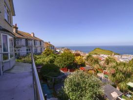 A view of houses and greenery with a hill and ocean in the background at Combe View in Ilfracombe