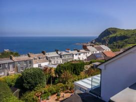 A coastal view with houses and greenery overlooking the sea and cliffs at Combe View in Ilfracombe