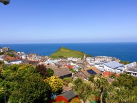 A coastal town with houses green hill and ocean in the background at Combe View in Ilfracombe