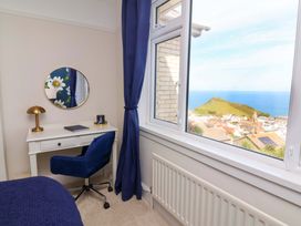 A bedroom with a desk and chair overlooking a coastal view at Combe View in Ilfracombe