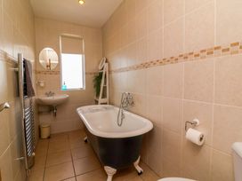 A bathroom with a bathtub, sink, and towel radiator at Combe View Ilfracombe