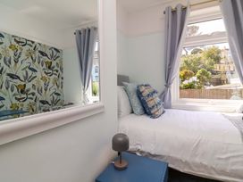 A bedroom with a bed, cushions, and a window at Combe View Ilfracombe