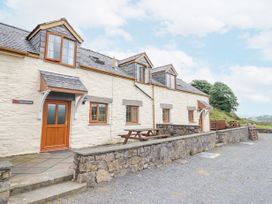 Stone cottage with wooden doors and windows picnic tables outside and stone wall at Llys-y-Wennol in Penmachno