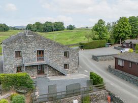 A stone building with a balcony in a grassy landscape at Bank Barn At Pound Farm Crook near Kendal