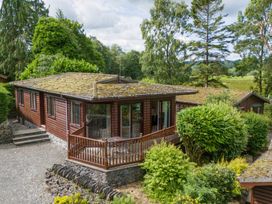 A log cabin with a balcony and surrounding trees at Lodge 3 At Pound Farm Crook near Kendal