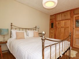 A bedroom with a metal bed and wooden wardrobe at The Old Village Chapel Crantock