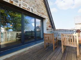 An outdoor seating area with wooden chairs and table at The Old Village Chapel in Crantock