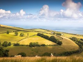 A landscape with fields, sheep, trees, and the sea at 23 Manleigh Park, Combe Martin
