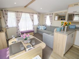 An open living and dining area with a dining table set for four and a gray sofa at Seabreeze Cottage in East Wittering