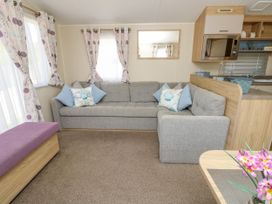 A living room with a gray sectional sofa and floral curtains at Seabreeze Cottage in East Wittering