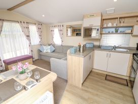 A kitchen and dining area with a sofa and curtains in a living room at Seabreeze Cottage in East Wittering
