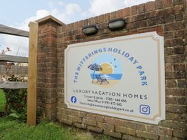 A brick wall with a sign for The Witterings Holiday Park luxury vacation homes in East Wittering