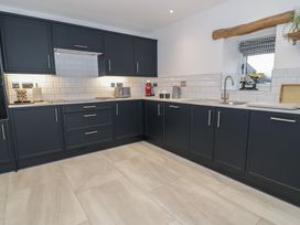 A kitchen with black cabinets and a sink at Y Stabl in Cerrigydrudion