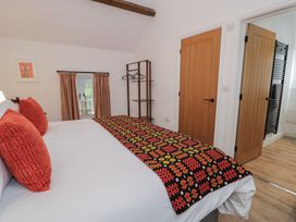 A bedroom with a bed and a clothes rack at Y Stabl in Cerrigydrudion