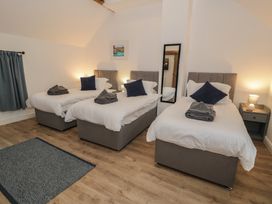 A bedroom with three beds and a mirror at Y Stabl in Cerrigydrudion
