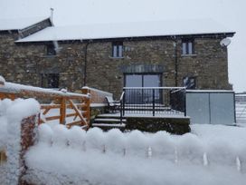 A house covered in snow with a railing and steps at Y Stabl in Cerrigydrudion