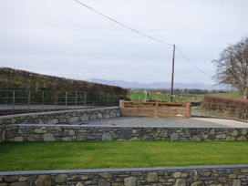 A grassy area with a stone wall and a wooden gate at Y Stabl in Cerrigydrudion