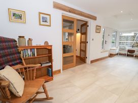 A living room with a rocking chair and bookshelf at Y Stabl in Cerrigydrudion