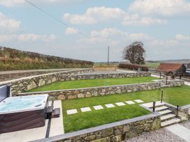 An outdoor area with a hot tub and stone walls at Y Côr in Cerrigydrudion