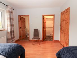 A bedroom with a chair and doors leading to a bathroom and storage area at Fort Lodge