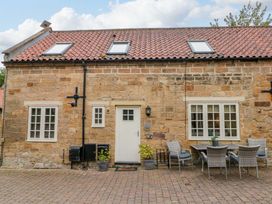 An exterior view of a stone house with a table and chairs at Clematis Cottage in Whitby