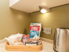 A kitchen counter with teapot and snacks at Clematis Cottage in Whitby