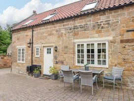 An outdoor seating area with a table and chairs at Clematis Cottage in Whitby