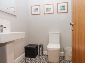 A bathroom with a toilet, sink, and framed pictures at Lower Moorwood Moorwood near Bovey Tracey