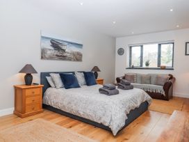 A bedroom with a bed, nightstand, sofa, and window at Lower Moorwood in Moorwood near Bovey Tracey