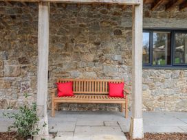 An outdoor seating area with a wooden bench at Lower Moorwood in Moorwood near Bovey Tracey