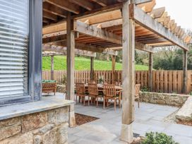 An outdoor patio with a dining table and wooden chairs at Lower Moorwood in Moorwood near Bovey Tracey