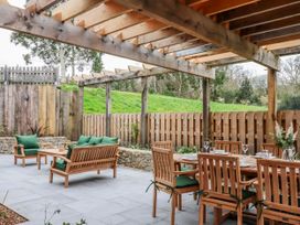 An outdoor dining area with a wooden table and chairs at Lower Moorwood in Moorwood near Bovey Tracey