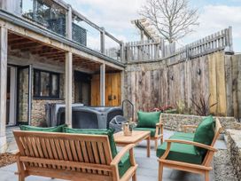 An outdoor seating area with green cushions and a hot tub at Lower Moorwood in Moorwood near Bovey Tracey