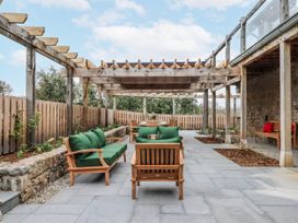 An outdoor patio with seating under a pergola at Lower Moorwood in Moorwood near Bovey Tracey