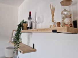 A shelf with wine bottle, glasses, decorative items and seashells at Plas Darien Apartment 7, Trearddur Bay
