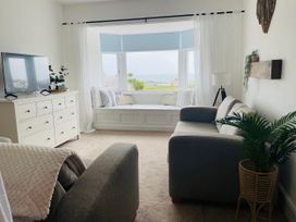 A living room with a television, sofa, and window seat at Plas Darien Apartment 7 in Trearddur Bay