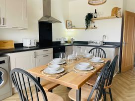 A kitchen with dining table set for dinner at Plas Darien Apartment 7 in Trearddur Bay