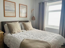 A bedroom with a bed and wall art at Plas Darien Apartment 7 Trearddur Bay