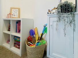 A storage area with a shelf of books and a basket of toys at Plas Darien Apartment 7 in Trearddur Bay