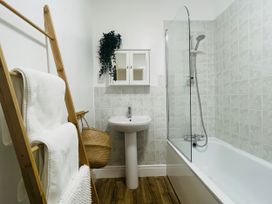 A bathroom with a bathtub, sink, and towel ladder at Plas Darien Apartment 7 Trearddur Bay
