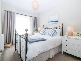 A bedroom with a bed, bedside table, and window at No.7 Plas Darien in Trearddur Bay