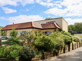 A house with a red tile roof and garden in front at 25 Manleigh Park in Combe Martin