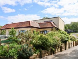 A house with a red tiled roof surrounded by greenery and a wooden fence at 26 Manleigh Park in Combe Martin