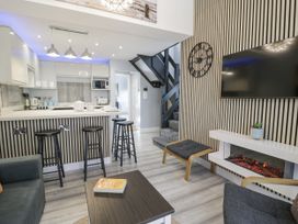 A living room with a kitchen area and a staircase at Harbwr Hideaway in Porthmadog