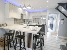 A kitchen with bar stools and modern appliances at Harbwr Hideaway in Porthmadog