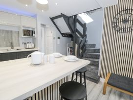 A kitchen with a staircase and dining area at Harbwr Hideaway in Porthmadog