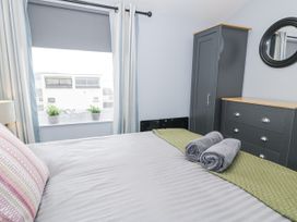 A bedroom with a bed, dresser and wardrobe at Harbwr Hideaway in Porthmadog