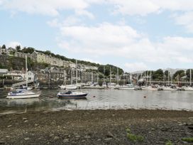 A marina with boats and buildings along the water at Harbwr Hideaway in Porthmadog